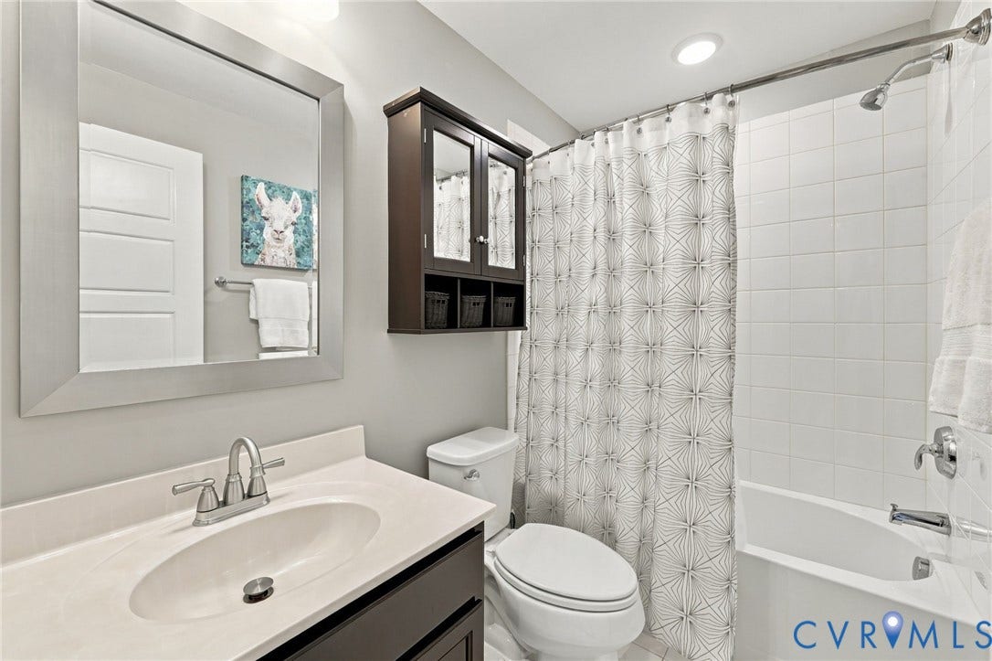 4223 Saunders Tavern Trail, #A, Henrico, VA 23233 Bathroom featuring a vanity with an integrated basin, a framed wall mirror, a dark wood-finish wall cabinet, and a tiled shower-tub combination with chrome fixtures
