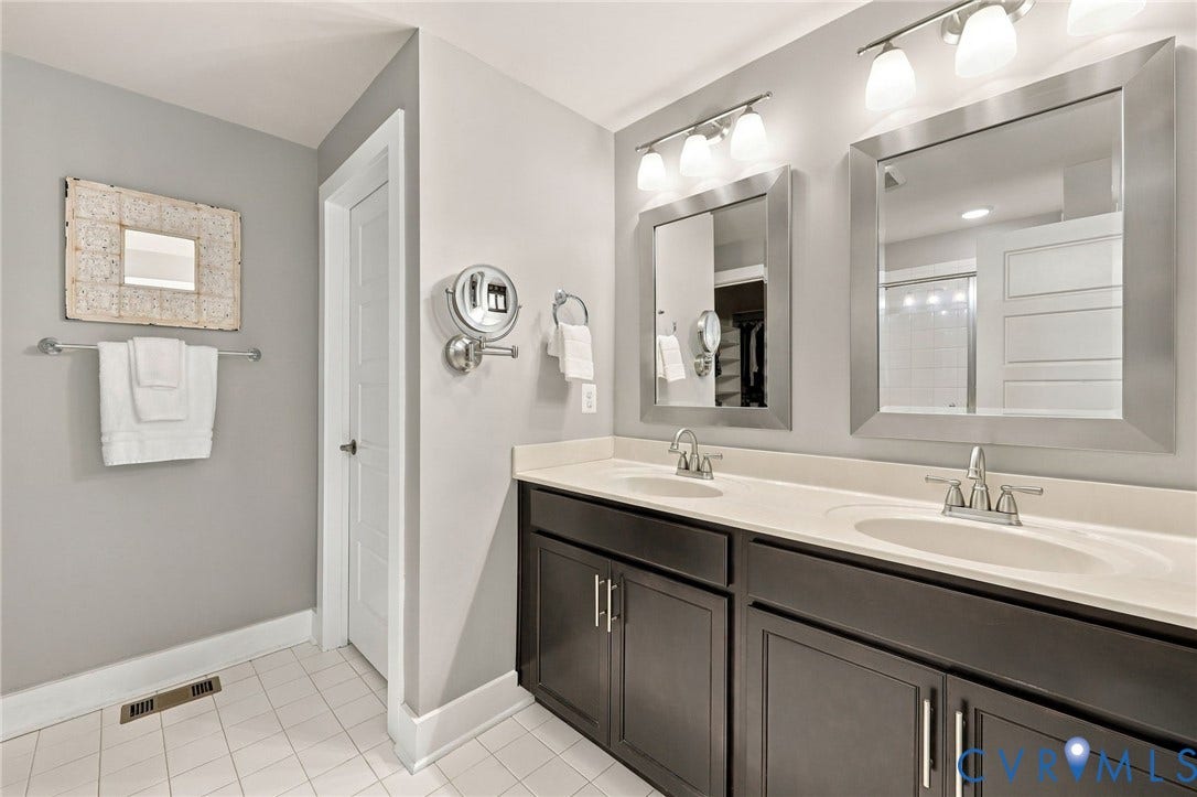 4223 Saunders Tavern Trail, #A, Henrico, VA 23233 Dual-vanity cabinet with dark-finish cabinetry, solid-surface countertop, integrated dual sinks, framed mirrors, and multi-light vanity fixtures