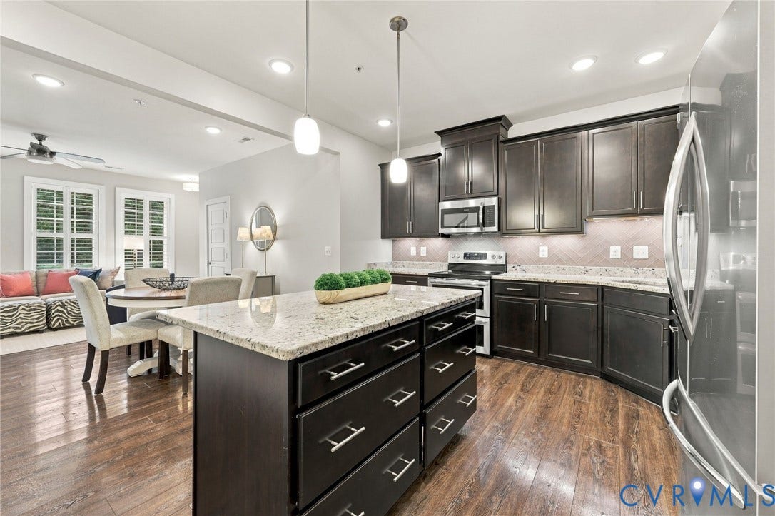 4223 Saunders Tavern Trail, #A, Henrico, VA 23233 Kitchen featuring espresso-toned cabinetry, stone countertops, a central island with storage, herringbone-patterned backsplash, and wood-finish flooring