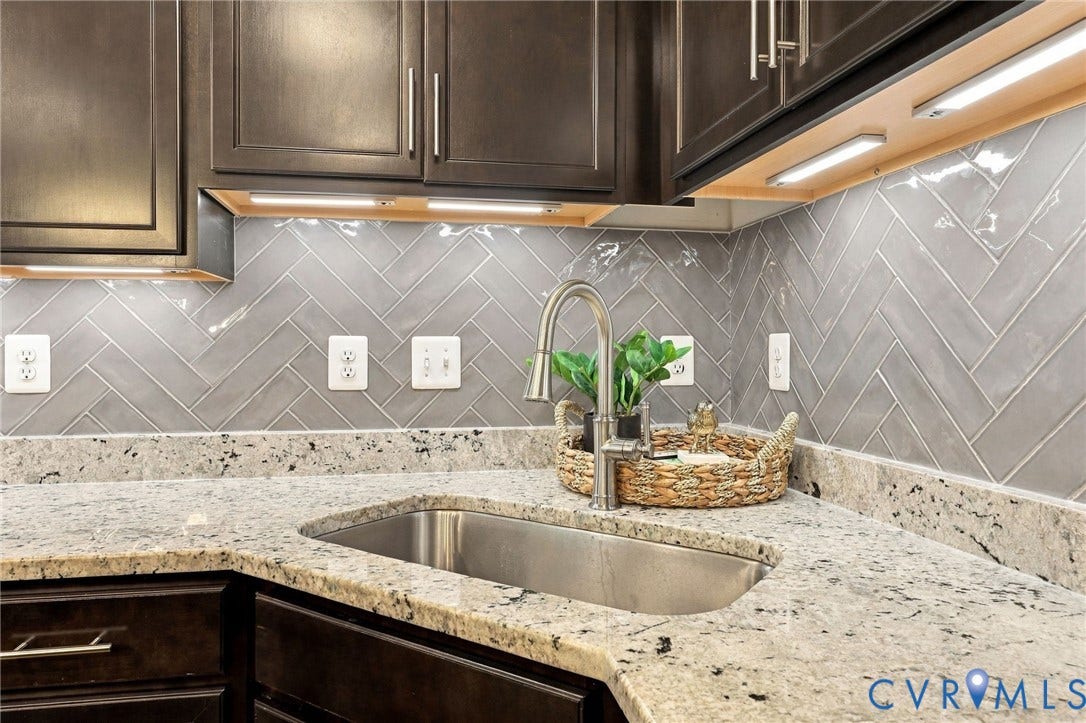 4223 Saunders Tavern Trail, #A, Henrico, VA 23233 Dark-toned cabinetry, light-colored stone-finish countertops, stainless steel undermount sink, gooseneck faucet, and gray herringbone-pattern tile backsplash
