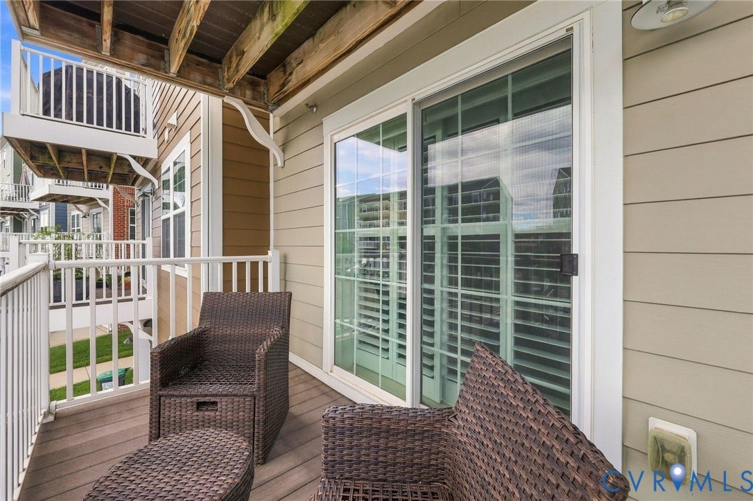 4223 Saunders Tavern Trail, #A, Henrico, VA 23233 Covered exterior deck featuring composite decking, white baluster railings, and a large sliding glass door with integrated shutters