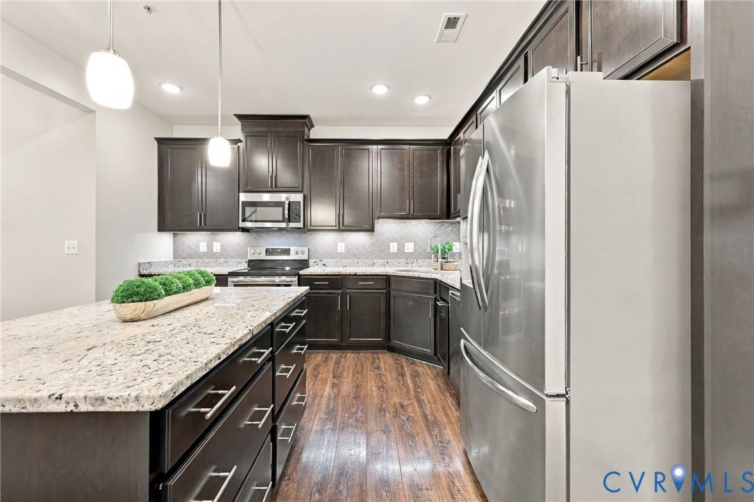 4223 Saunders Tavern Trail, #A, Henrico, VA 23233 Kitchen featuring dark wood cabinetry, light-toned stone countertops, an expansive center island, stainless steel appliances, and wood-finish flooring