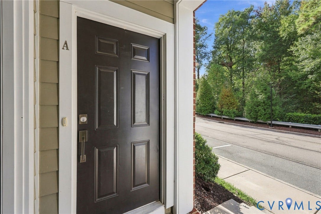 4223 Saunders Tavern Trail, #A, Henrico, VA 23233 Six-panel dark-finish entry door with metallic hardware, set within a white trim surround and light-toned horizontal siding