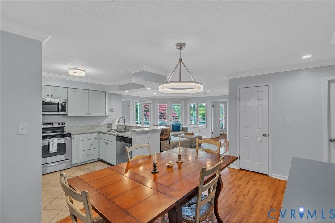 Kitchen featuring stainless steel appliances, light-toned cabinetry, stone-finish countertops, crown molding, and a modern circular chandelier