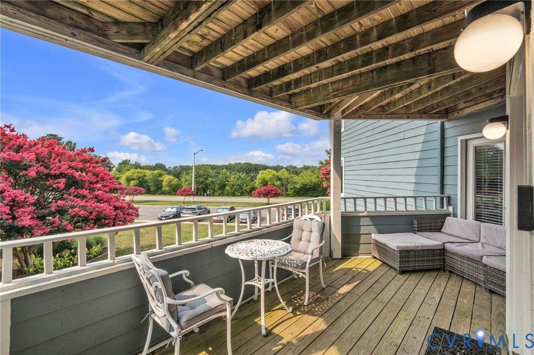 Covered wooden deck featuring exposed rafters, lap siding, and a white picket-style railing