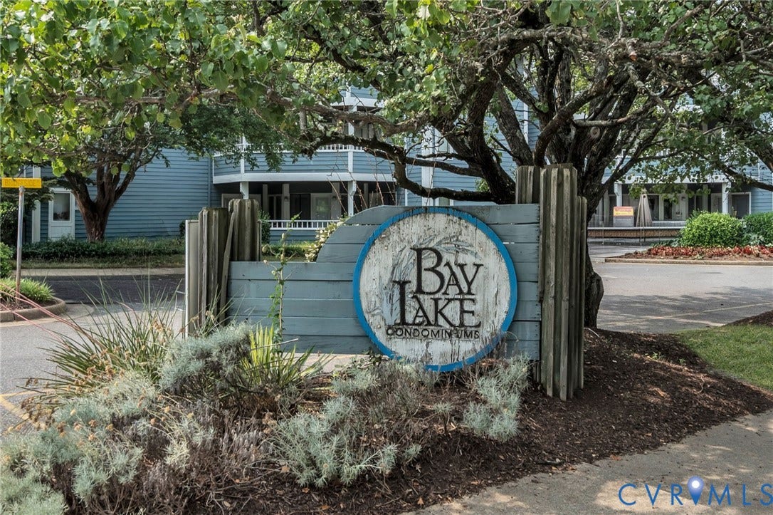 Custom signage for Bay Lake Condominiums featuring wood-plank construction and mature tree-lined landscaping