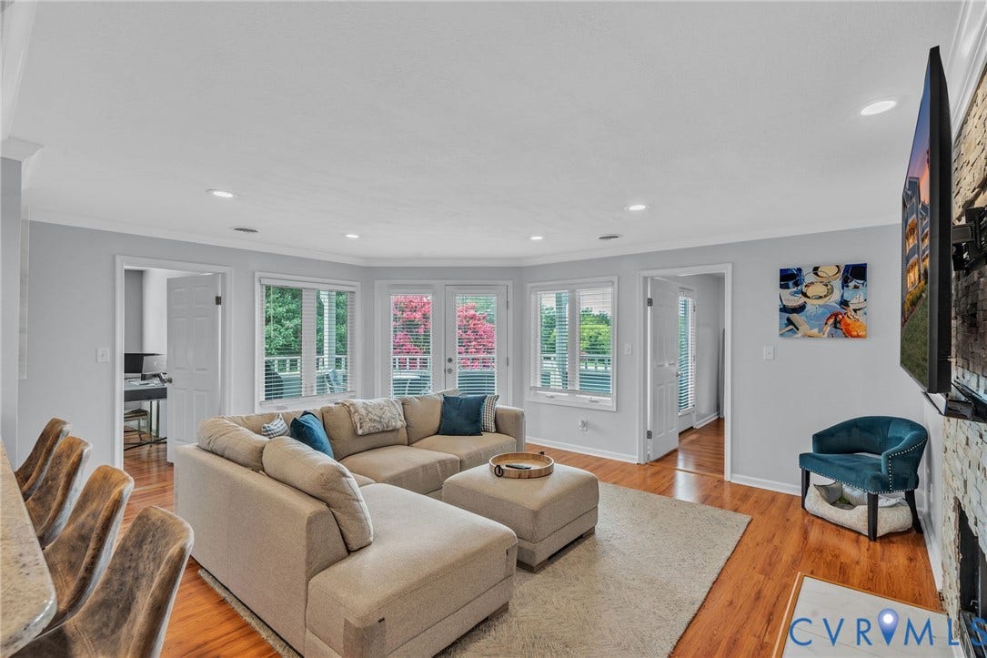 Living area featuring wood-finish flooring, recessed lighting, double glass doors, and a natural stone fireplace surround