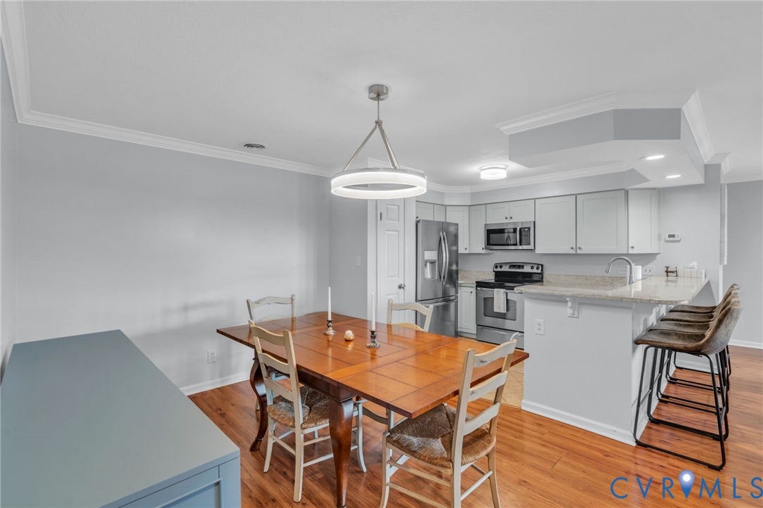 Kitchen featuring white shaker cabinetry, stone-finish countertops, stainless steel appliances, breakfast bar, and wood-finish flooring