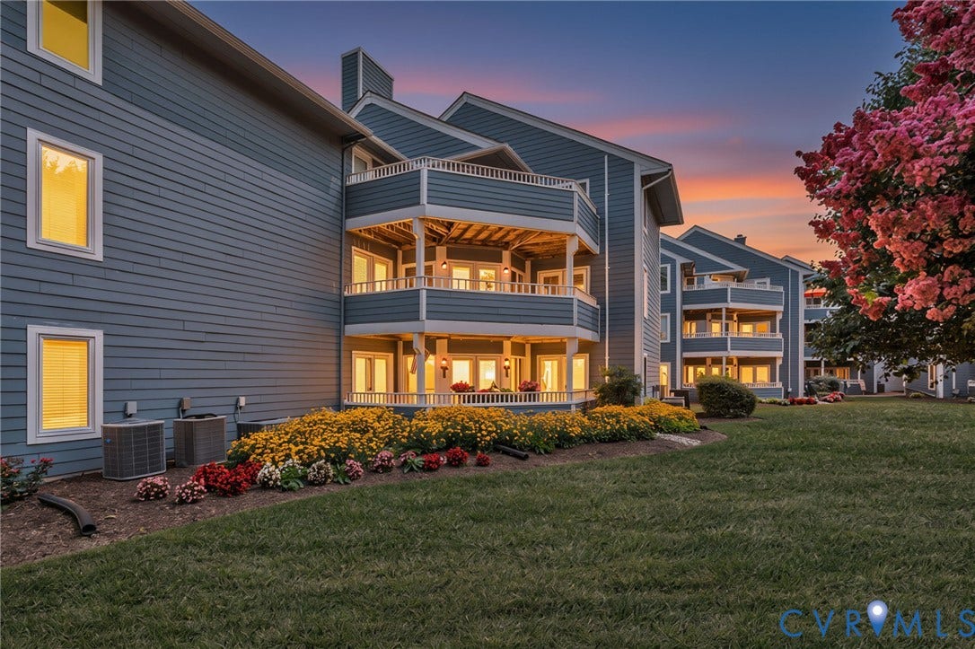 Multi-story exterior featuring lap siding, stacked private balconies with railings, and manicured landscaping