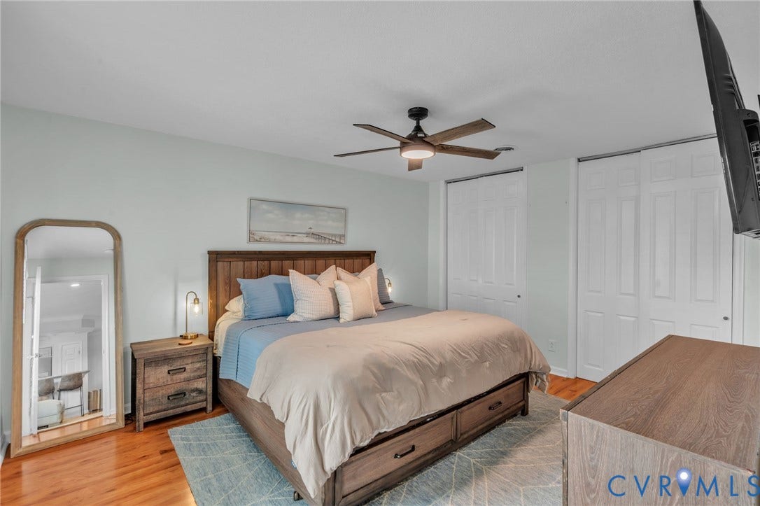 Room featuring wood-finish flooring, a central ceiling fan with integrated lighting, and dual white paneled closets
