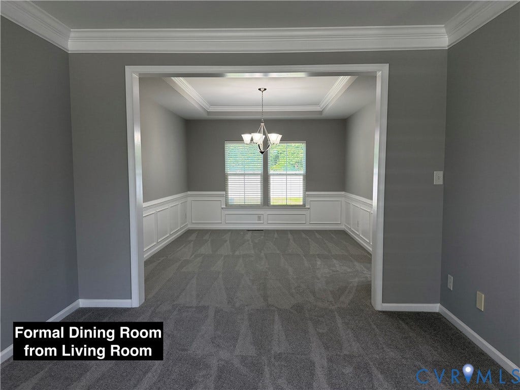 Tray ceiling, crown molding, white wainscoting, and a multi-light chandelier