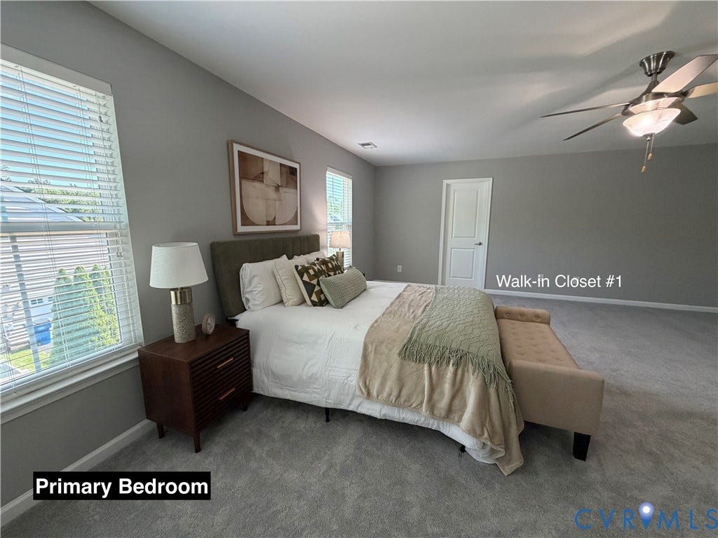 Spacious room featuring neutral carpeting, a multi-blade ceiling fan with integrated lighting, and dual windows