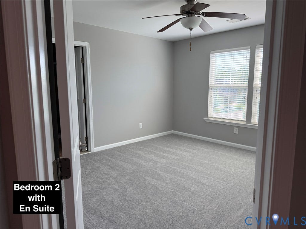 Neutral interior featuring gray carpeting, dual windows with installed blinds, and a ceiling fan with integrated lighting