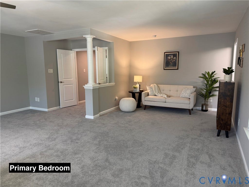 Open floor plan featuring neutral wall tones, plush wall-to-wall carpeting, a decorative architectural column, and dual-panel interior doors