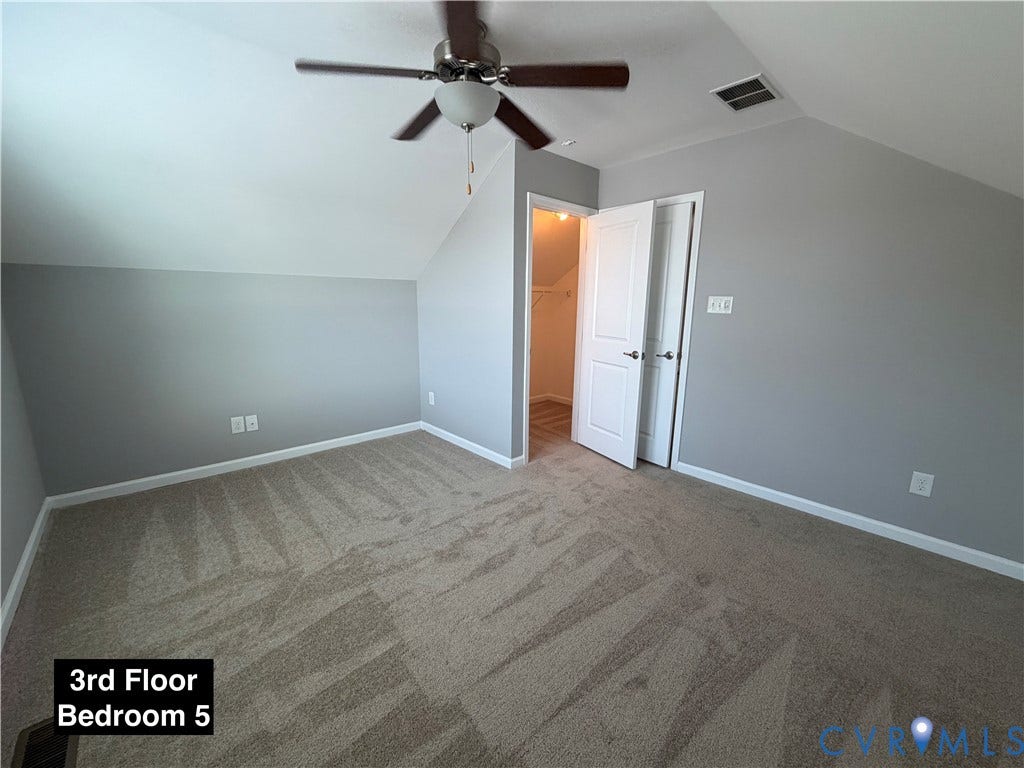 Room featuring neutral wall-to-wall carpeting, vaulted ceilings, a ceiling fan with integrated lighting, and a reach-in closet with double doors