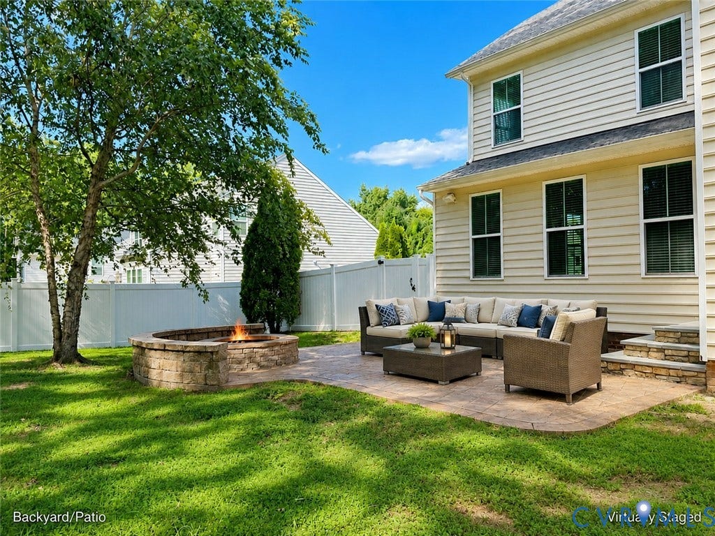 Expansive paver patio featuring a built-in stone fire pit and mature landscaping
