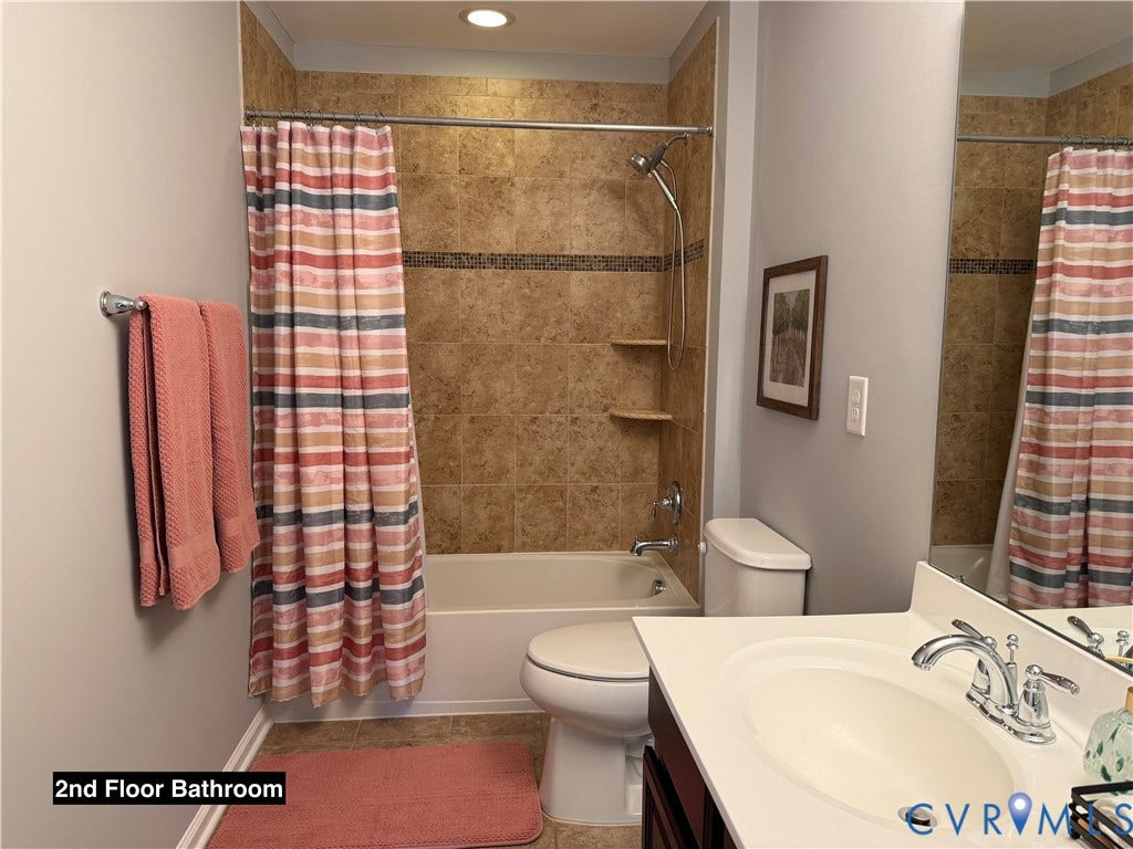 Bathroom featuring a combination bathtub and shower with tile surround, built-in shelving, chrome fixtures, and a vanity with an integrated basin