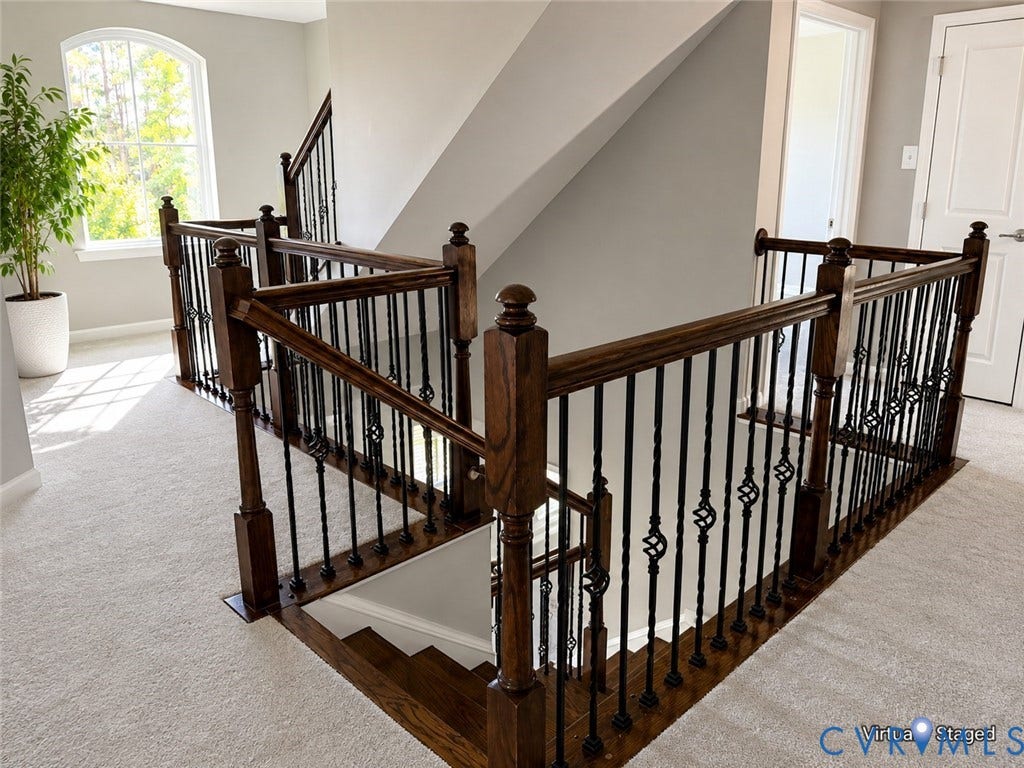 Elegant staircase featuring hardwood treads, dark wood handrails and posts, and decorative wrought iron balusters, with an open, visually striking design
