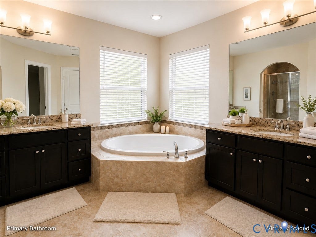 Spacious primary bathroom featuring a **dual vanity with dark wood cabinetry and granite countertops**, tiled flooring, a large corner soaking tub, abundant natural light, and a walk-in shower, creating a bright and inviting retreat.