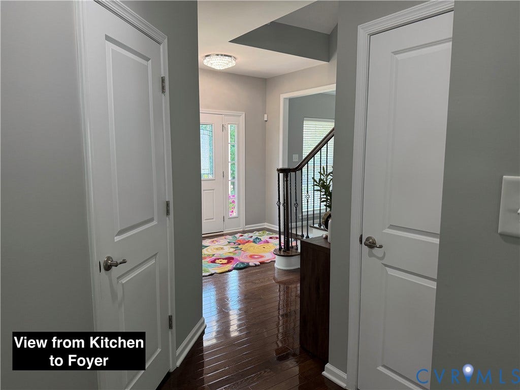 Entryway featuring wood-finish flooring, white panel doors, staircase with decorative metal balusters, and a multi-light flush-mount ceiling fixture