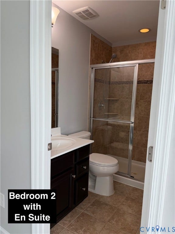 Bathroom featuring a dark-finish wood vanity with a white countertop, walk-in shower with tile surround and sliding glass doors, and tile flooring