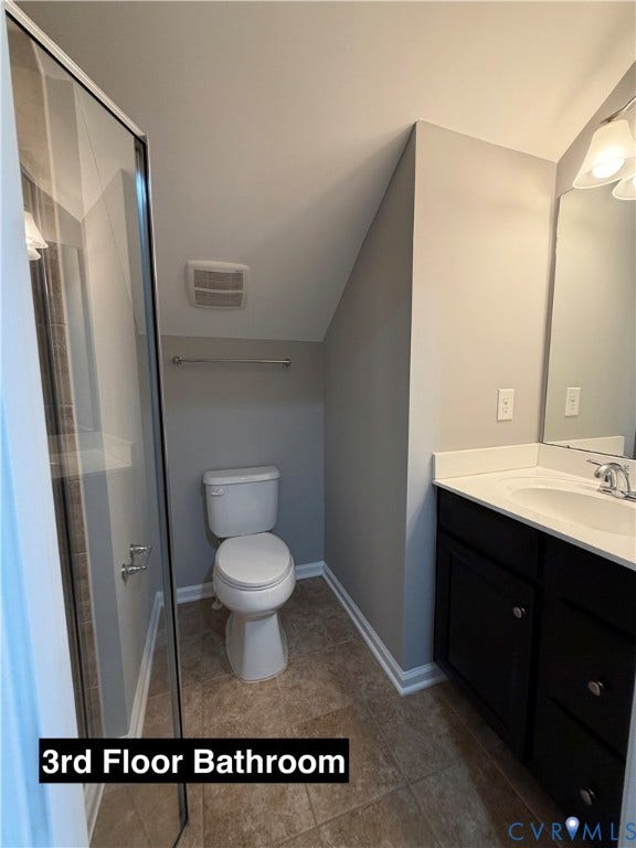 Bathroom featuring a glass-enclosed shower, dark-finish vanity cabinet, integrated sink with light-toned countertop, and ceramic tile flooring