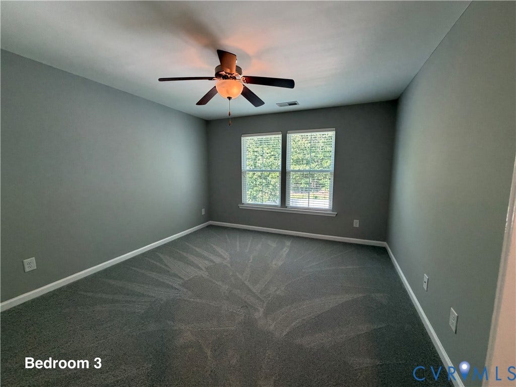 Room featuring neutral wall tones, wall-to-wall carpeting, dual windows, and a ceiling fan with integrated lighting