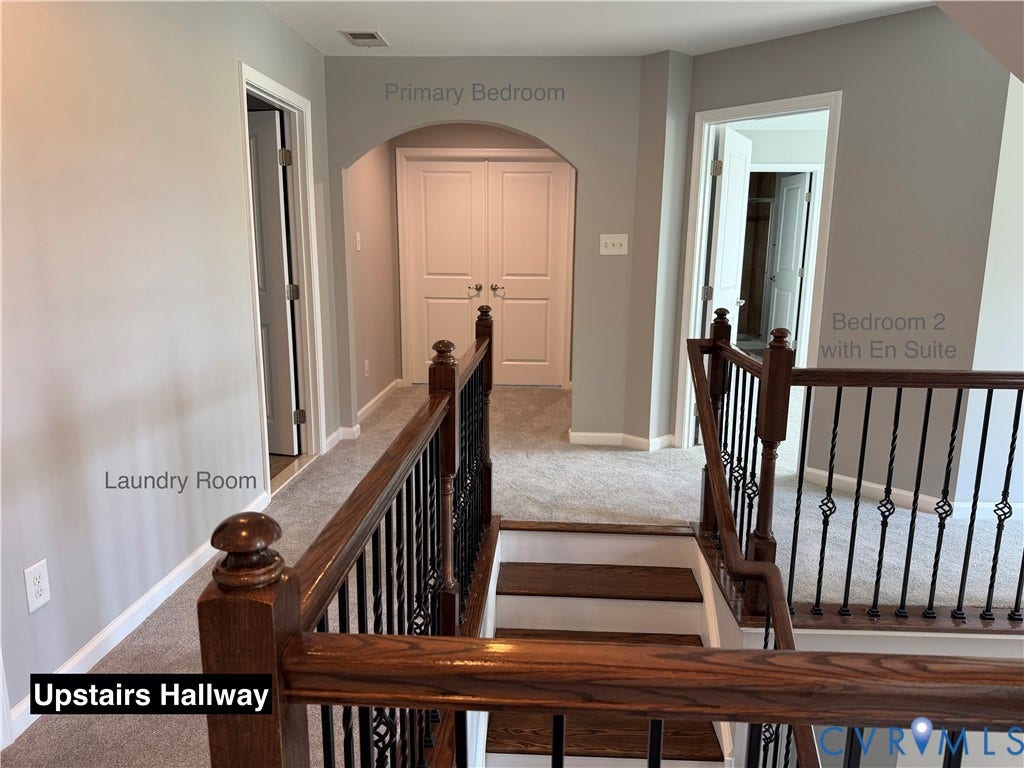 Staircase featuring dark wood handrails with decorative black iron balusters, arched entryway, and neutral carpeting