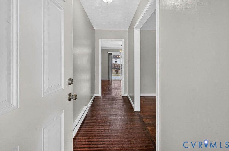 Entryway featuring dark-stained wood-finish flooring, neutral grey wall paint, and white door trim