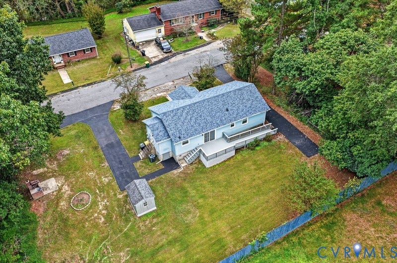 Exterior features include a shingled roof, asphalt driveway, elevated rear deck, detached storage structure, and fenced perimeter