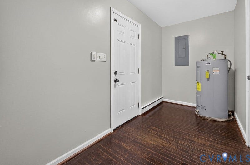Utility room featuring wood-finish flooring, a six-panel door, and a built-in electrical service panel