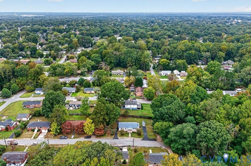 Aerial perspective showcasing a detached residential property with an asphalt driveway and mature tree canopy throughout the surrounding neighborhood