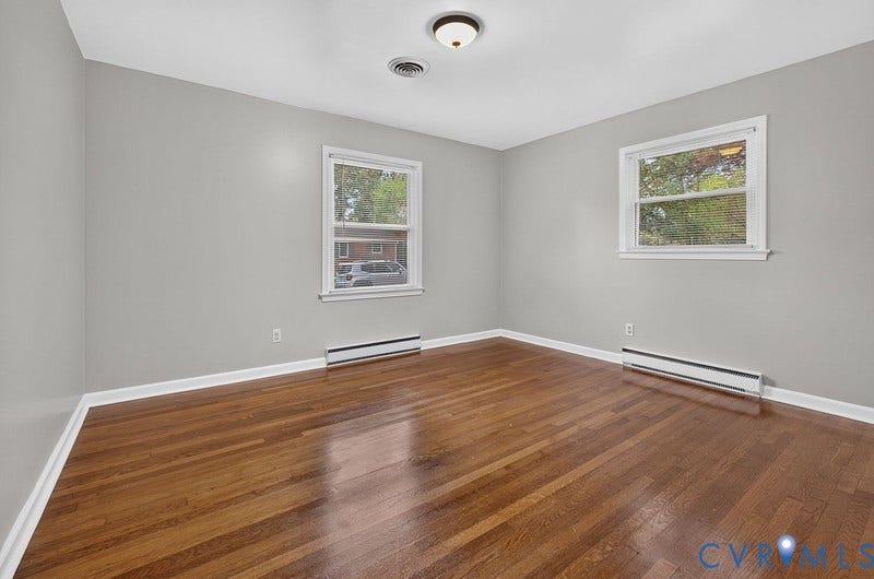 Room featuring wood-finish flooring, neutral wall paint, and two double-hung windows
