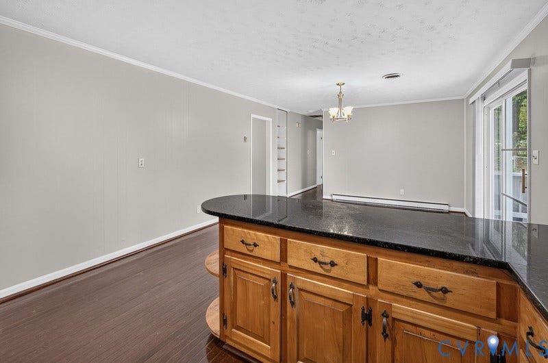 Kitchen island with a dark stone countertop, wood-finish cabinetry, dark wood-finish flooring, and sliding glass doors