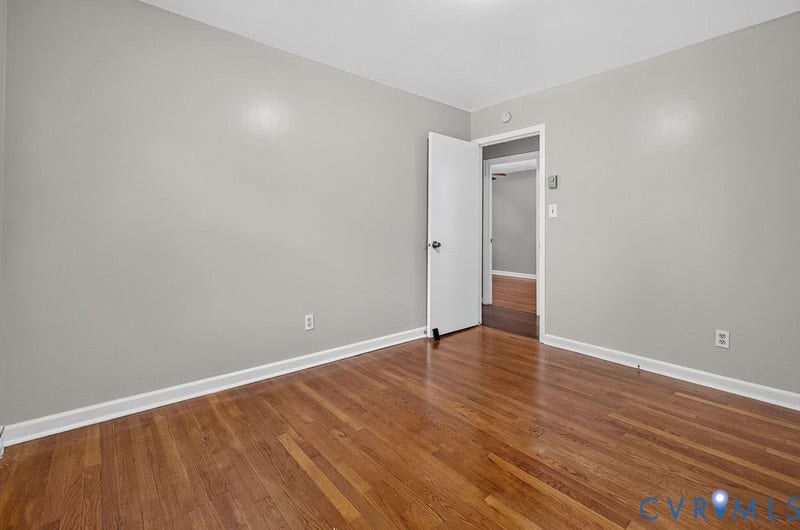 Room featuring wood-finish flooring and neutral-toned wall paint