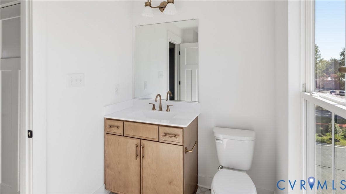 11612 Switch Drive, Midlothian Depot, Midlothian, VA 23113 Vanity featuring light wood-finish cabinetry, a rectangular sink with a white surface, metal hardware, a wall-mounted mirror, and a dual-light fixture
