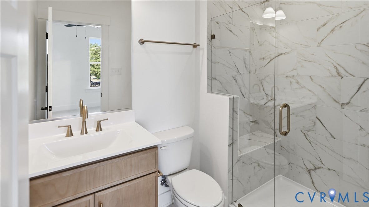 11612 Switch Drive, Midlothian Depot, Midlothian, VA 23113 Bathroom featuring a vanity with an integrated sink and metal-finish faucet, a glass-enclosed shower with full-height stone-patterned tile surround, and a wall-mounted towel bar
