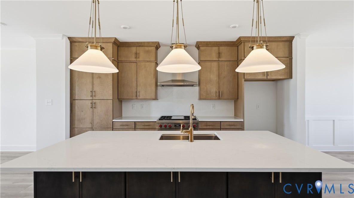 11612 Switch Drive, Midlothian Depot, Midlothian, VA 23113 Kitchen featuring a large island with a quartz countertop, wood-finish cabinetry, stainless steel gas range, brass-tone hardware, and trio of pendant light fixtures