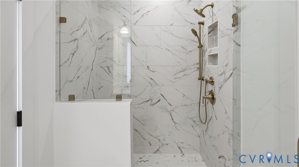 11612 Switch Drive, Midlothian Depot, Midlothian, VA 23113 Walk-in shower featuring large-format stone-patterned tile, frameless glass enclosure, built-in recessed wall shelving, and gold-tone hardware including a fixed rain-style showerhead and handheld sprayer