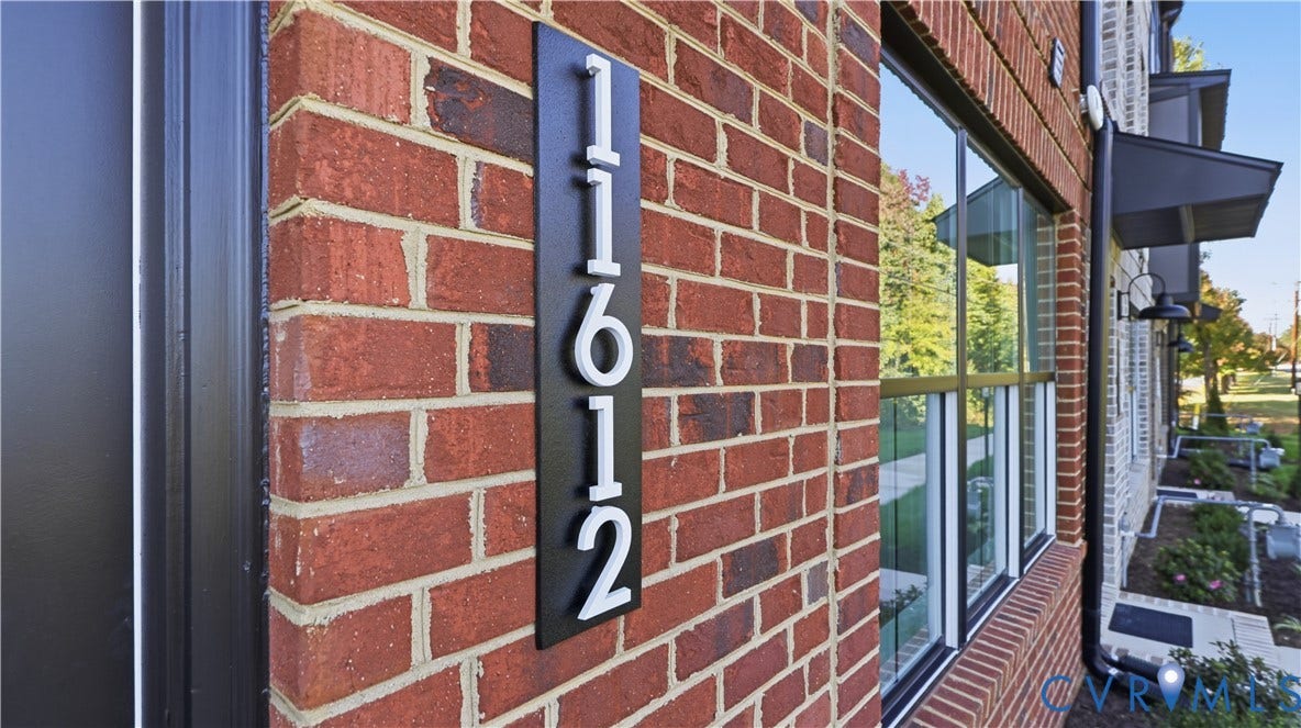 11612 Switch Drive, Midlothian Depot, Midlothian, VA 23113 Red brick exterior featuring metal-framed windows, a matte black house number plaque with dimensional numbering, and dark-finished exterior light fixtures