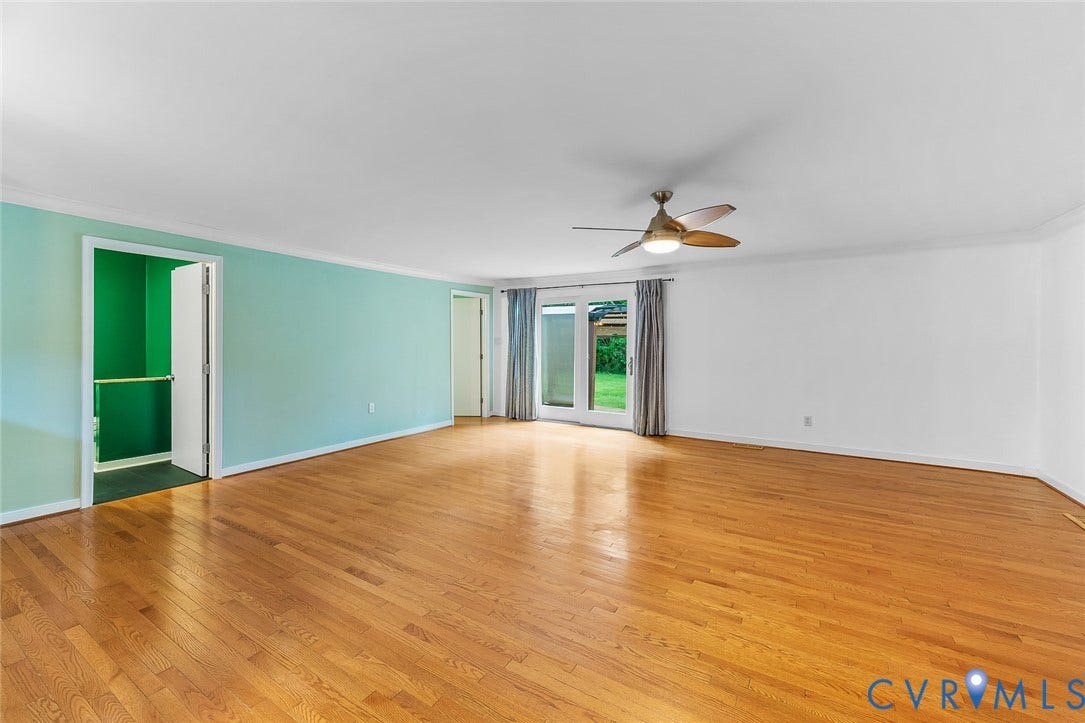 Spacious interior featuring wood-finish flooring, a ceiling-mounted light fixture with fan, and glass-paneled patio doors