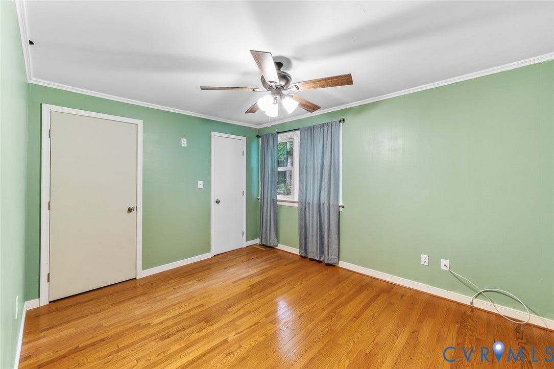 Room featuring wood-finish flooring, a ceiling fan with integrated lighting, and two interior doors
