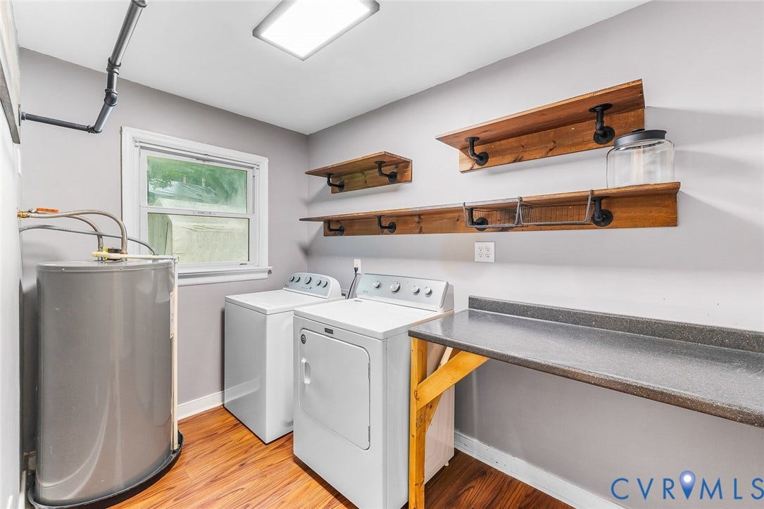Wood-finish flooring, industrial-style wall-mounted shelving, built-in workspace with a solid surface countertop, and a double-pane window