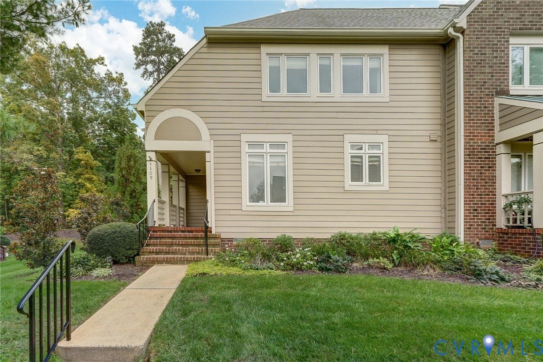 1109 Lakeland Circle, Henrico, VA 23229 Exterior facade featuring horizontal siding and brick masonry accents, arched covered entryway, multi-pane windows, and a concrete walkway