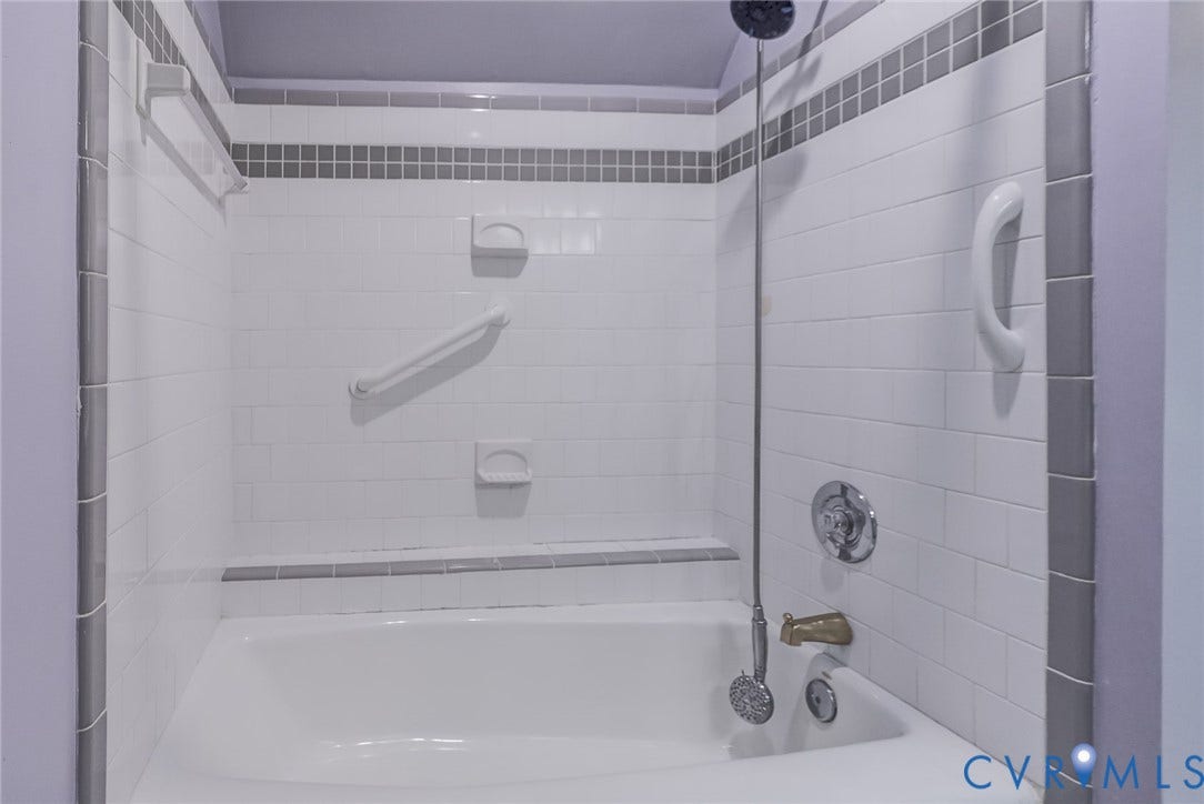 1109 Lakeland Circle, Henrico, VA 23229 White subway tile shower surround with gray accent tiling, built-in soap dishes, wall-mounted hardware, and a tub with a handheld shower fixture