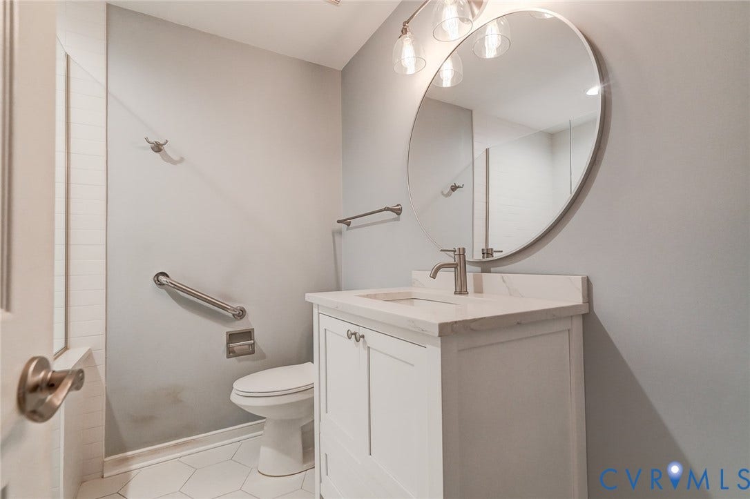 1109 Lakeland Circle, Henrico, VA 23229 Bathroom featuring a white vanity cabinet with a stone-top integrated sink, round frameless mirror, three-light fixture, and hexagonal tile flooring