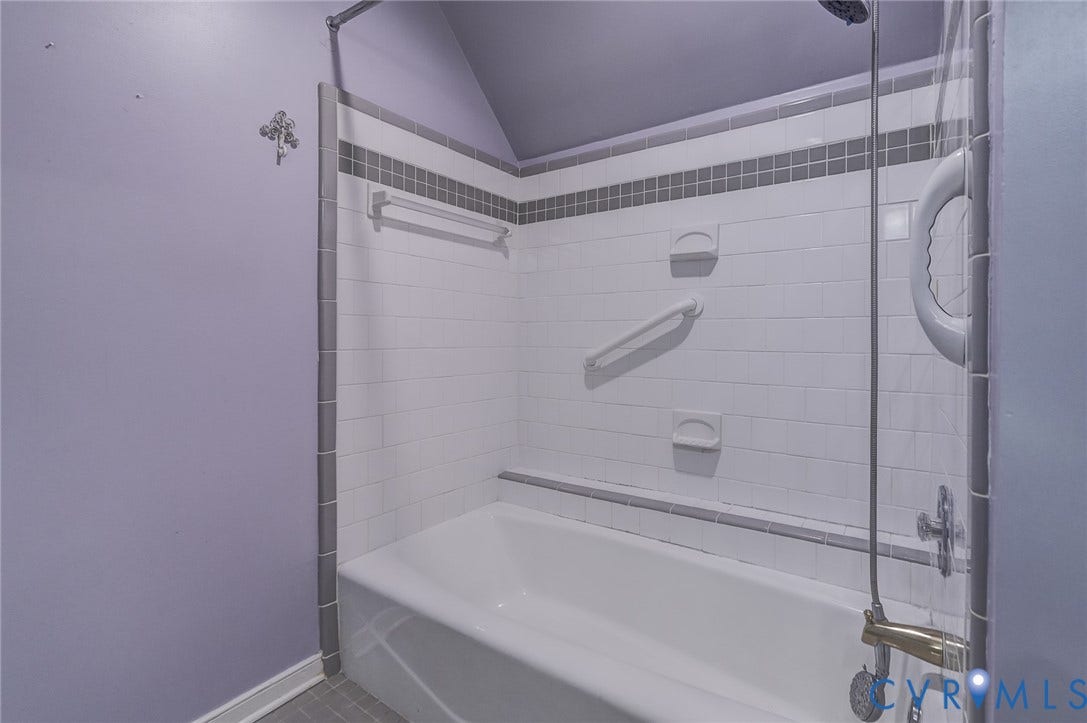 1109 Lakeland Circle, Henrico, VA 23229 Bathtub surround featuring white subway tile, a gray accent border, built-in soap dishes, a mounted grab bar, and a handheld shower fixture