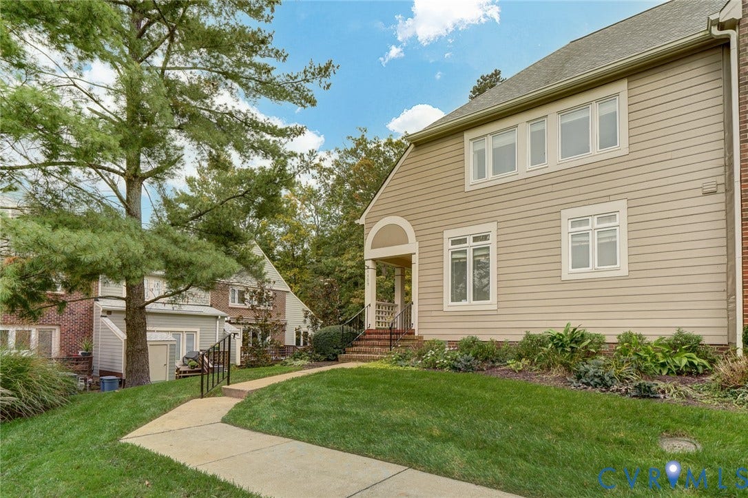 1109 Lakeland Circle, Henrico, VA 23229 Exterior featuring beige horizontal siding, multi-paned windows, a covered entryway with an arched detail, and a concrete walkway bordered by established greenery