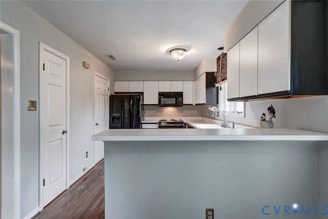 1109 Lakeland Circle, Henrico, VA 23229 Kitchen featuring white cabinetry, a breakfast bar with a solid surface countertop, wood-finish flooring, and integrated black appliances including an over-the-range microwave