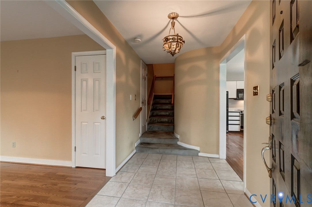 1109 Lakeland Circle, Henrico, VA 23229 Entryway featuring a decorative hanging light fixture, tile flooring, wood-finish flooring, a paneled door, and a staircase with a wooden handrail